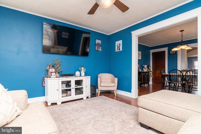 living room with baseboards, crown molding, ceiling fan, and wood finished floors