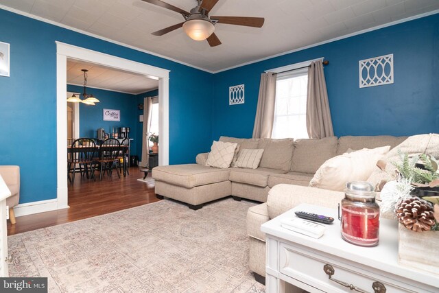 living area featuring baseboards, a ceiling fan, wood finished floors, and crown molding