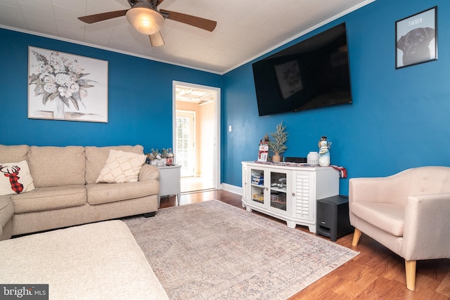 living room with a ceiling fan, crown molding, wood finished floors, and baseboards