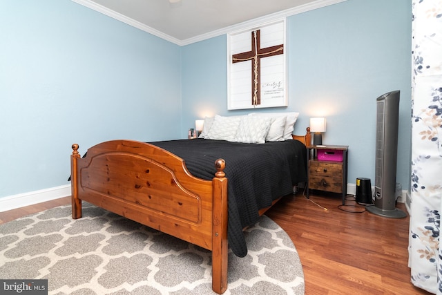 bedroom with crown molding, baseboards, and wood finished floors