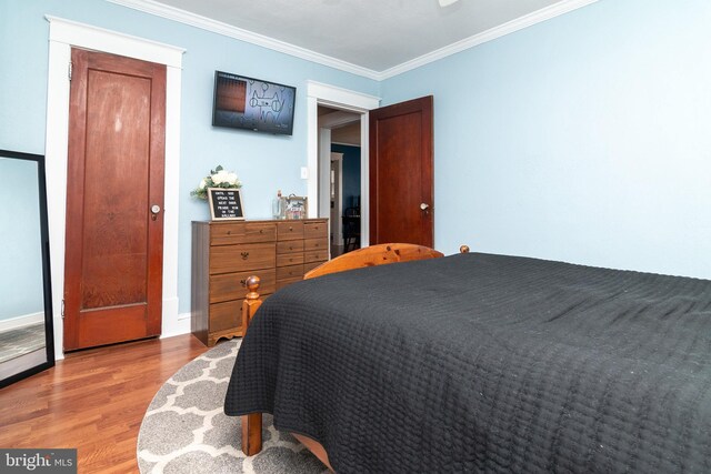 bedroom with baseboards, wood finished floors, and crown molding