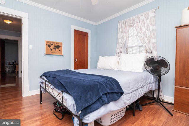 bedroom featuring crown molding, wood finished floors, baseboards, and ceiling fan