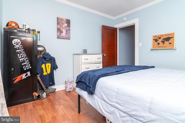 bedroom with crown molding, baseboards, and wood finished floors