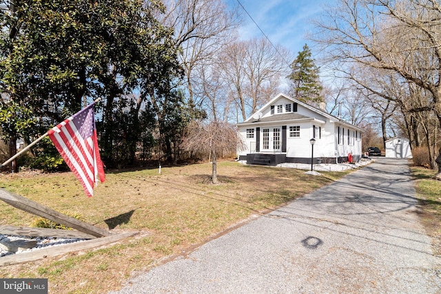 exterior space with an outbuilding, driveway, entry steps, french doors, and a lawn