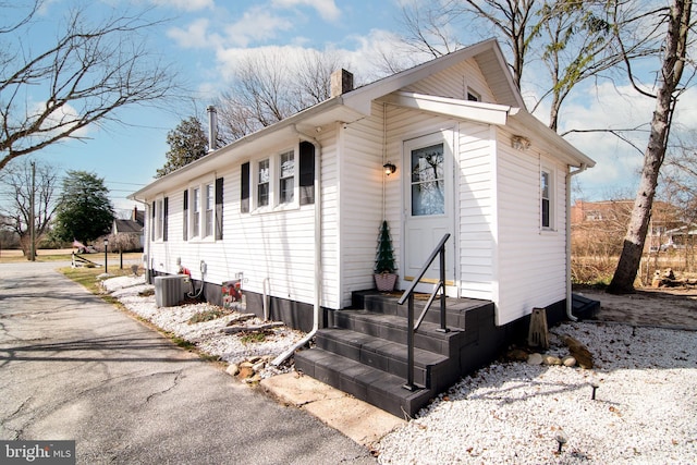 view of front of property featuring central AC unit and a chimney