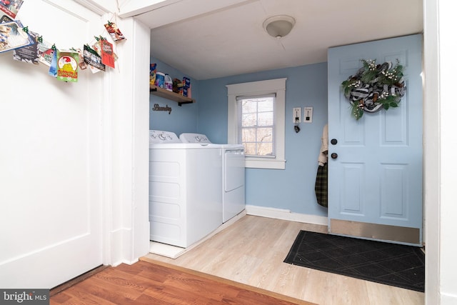 washroom featuring laundry area, wood finished floors, baseboards, and washing machine and clothes dryer