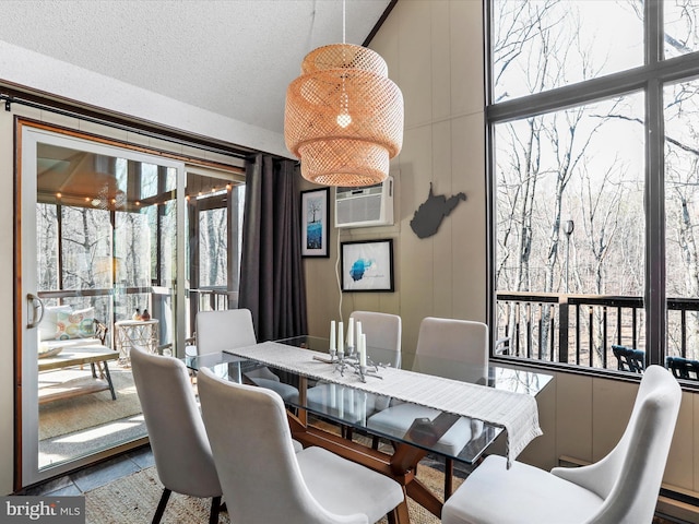 dining space with a textured ceiling and a wall unit AC