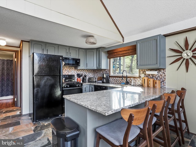 kitchen with black appliances, a peninsula, gray cabinets, and backsplash