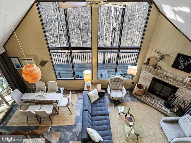 living area featuring a brick fireplace, vaulted ceiling, a ceiling fan, and a healthy amount of sunlight