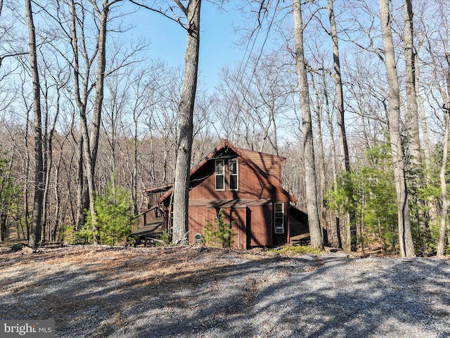 view of property exterior featuring a barn and a view of trees