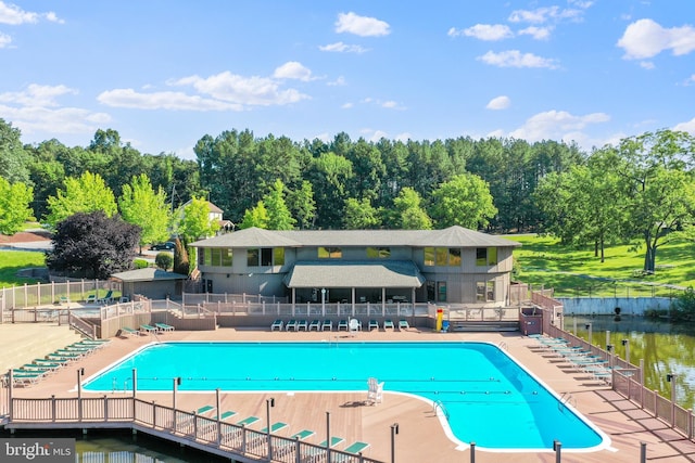 pool featuring a patio, fence, and a water view