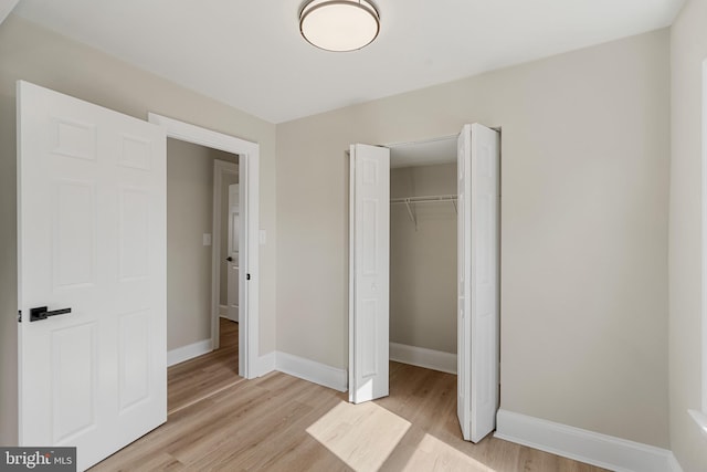 unfurnished bedroom with a closet, baseboards, and light wood-style floors