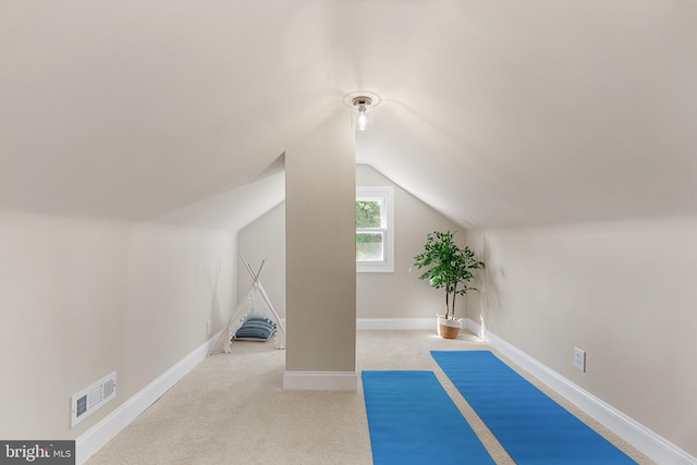 exercise area featuring vaulted ceiling, carpet flooring, baseboards, and visible vents