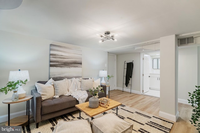 living room featuring light wood-type flooring, visible vents, and baseboards