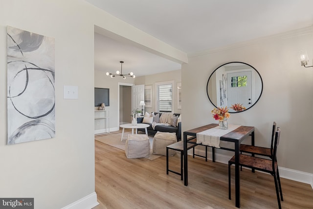 dining area with light wood-type flooring, plenty of natural light, a notable chandelier, and baseboards