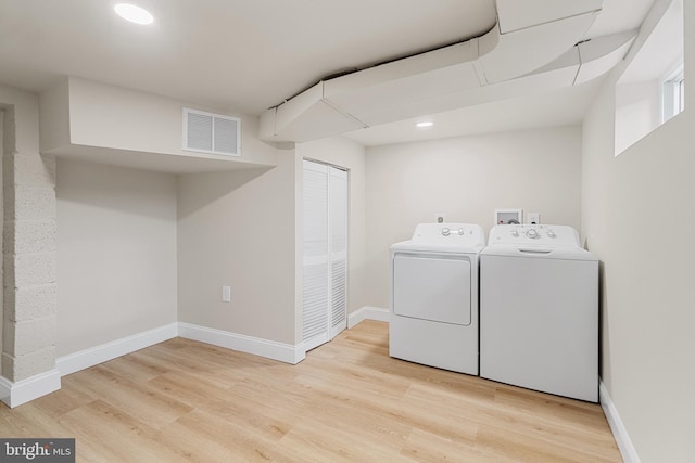 laundry area featuring visible vents, baseboards, wood finished floors, and washer and clothes dryer