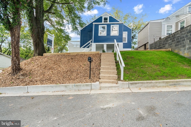 view of front facade with a front lawn, stairs, and fence