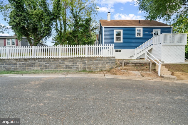 view of front facade with stairway, a fenced front yard, and a chimney