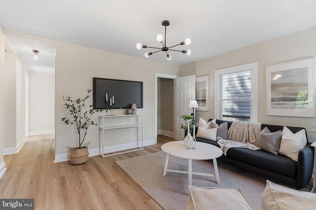 living room with light wood finished floors, baseboards, and an inviting chandelier