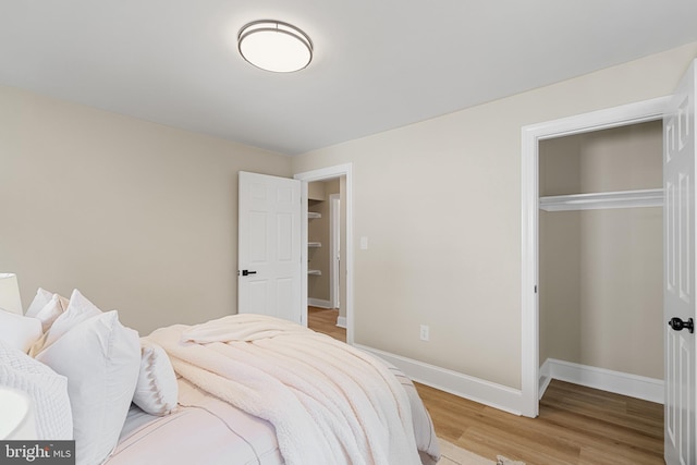 bedroom with light wood finished floors, a closet, and baseboards