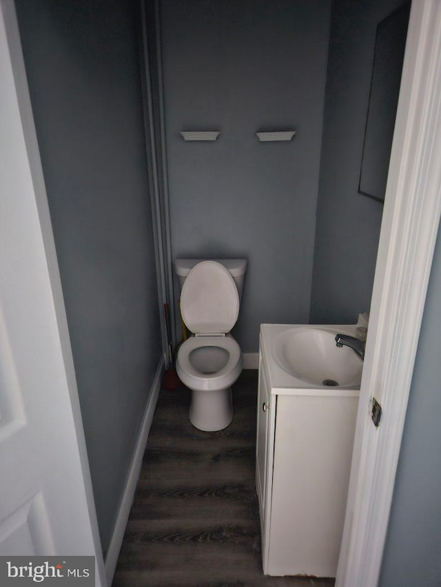 bathroom featuring vanity, toilet, wood finished floors, and baseboards