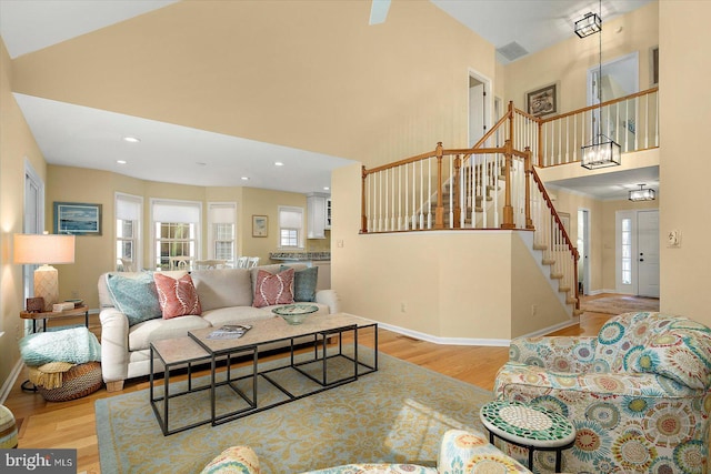 living room featuring baseboards, a high ceiling, wood finished floors, and stairs