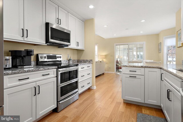 kitchen featuring recessed lighting, stainless steel appliances, light wood-style floors, white cabinets, and light stone countertops