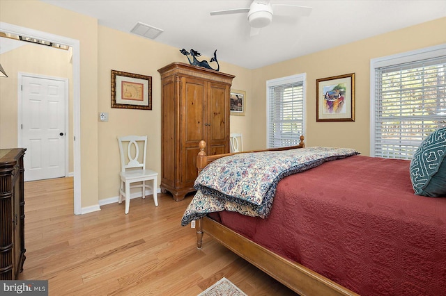 bedroom with a ceiling fan, light wood-style floors, visible vents, and baseboards