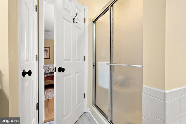 full bathroom featuring a shower stall, ensuite bathroom, and wood finished floors