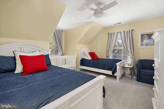 carpeted bedroom with lofted ceiling, multiple windows, visible vents, and ceiling fan