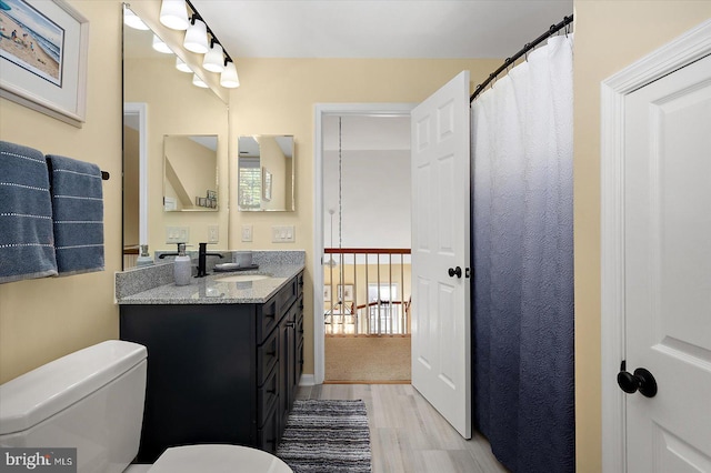 full bath featuring toilet, vanity, and wood finished floors