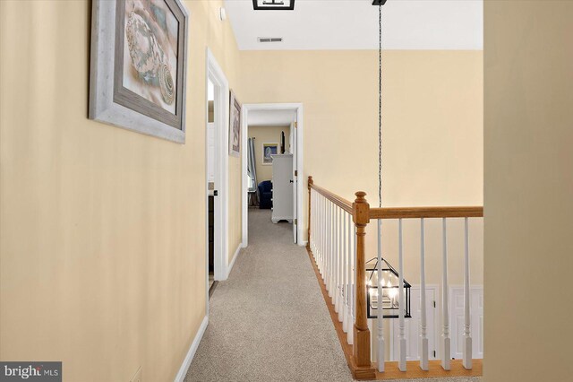 hallway featuring carpet, visible vents, and baseboards