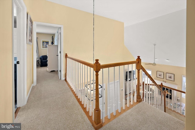 hallway with lofted ceiling, an upstairs landing, and carpet floors