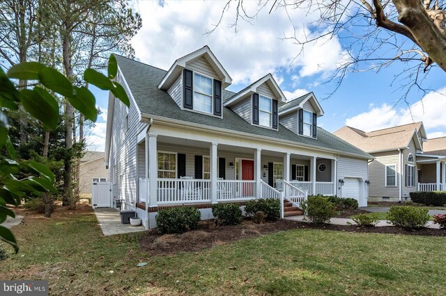 cape cod-style house with a porch, a garage, roof with shingles, and a front lawn