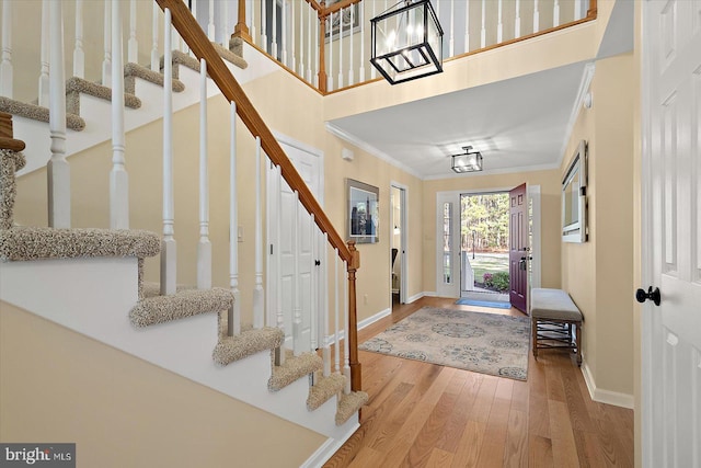 entryway featuring stairway, wood finished floors, baseboards, and ornamental molding