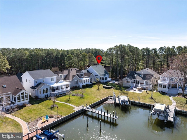 drone / aerial view featuring a forest view, a water view, and a residential view