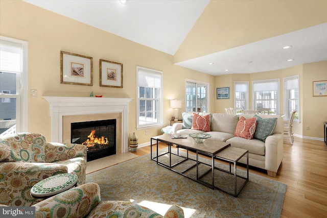 living area featuring baseboards, recessed lighting, a fireplace, wood finished floors, and high vaulted ceiling