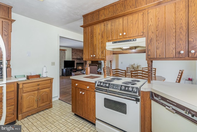 kitchen with brown cabinets, under cabinet range hood, white electric range oven, a fireplace, and light countertops