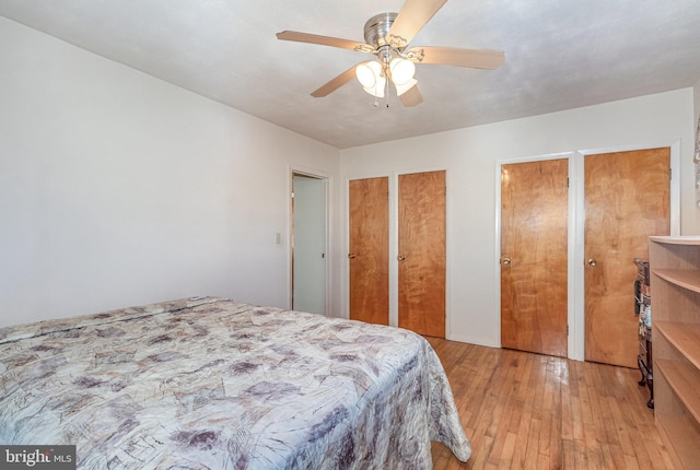 bedroom featuring a ceiling fan, light wood-style floors, and multiple closets