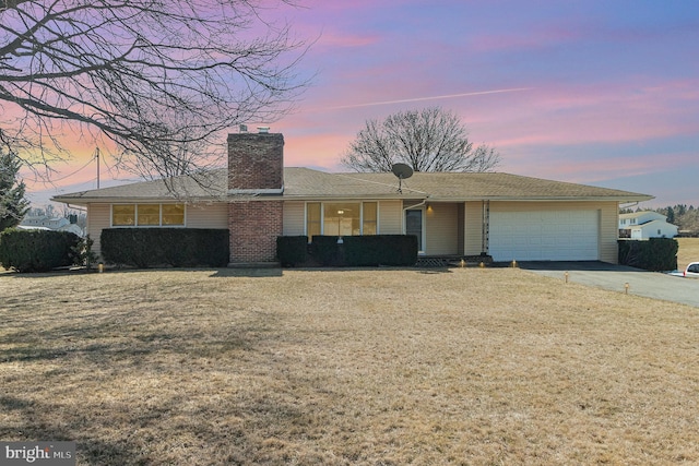 ranch-style home featuring a garage, a front lawn, concrete driveway, and a chimney