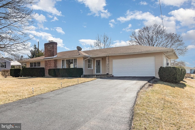 ranch-style home with a front yard, aphalt driveway, a garage, and a chimney