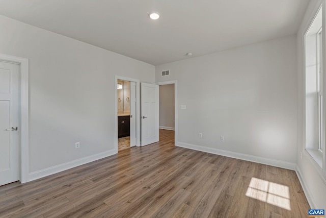 unfurnished bedroom with light wood-type flooring, visible vents, and baseboards