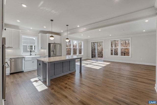 kitchen with a center island, crown molding, stainless steel appliances, white cabinetry, and a sink