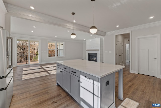 kitchen featuring light wood finished floors, ornamental molding, gray cabinetry, stainless steel refrigerator, and open floor plan