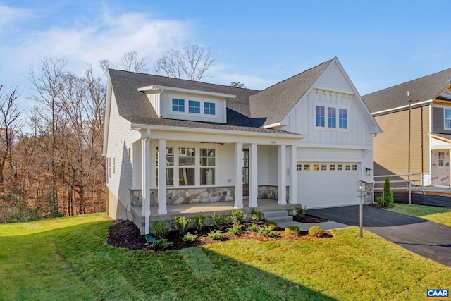 view of front of property featuring a porch, a front lawn, a garage, aphalt driveway, and board and batten siding