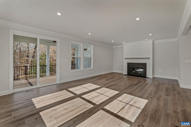 unfurnished living room featuring wood finished floors, a large fireplace, baseboards, and ornamental molding