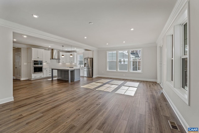 unfurnished living room featuring visible vents, dark wood-type flooring, ornamental molding, recessed lighting, and baseboards