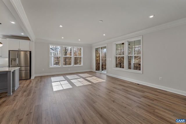 unfurnished living room featuring recessed lighting, wood finished floors, baseboards, and ornamental molding