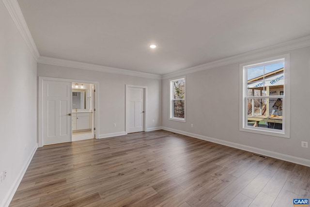 spare room with baseboards, wood finished floors, visible vents, and ornamental molding