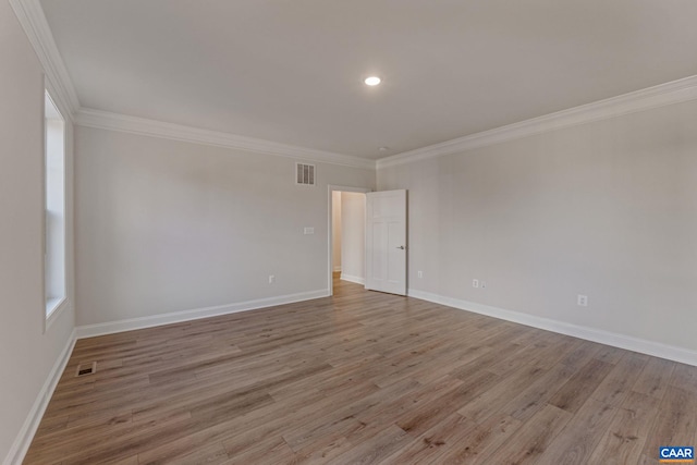 unfurnished room with crown molding, wood finished floors, visible vents, and baseboards